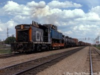 Long before its time on the Southern Ontario Railway as SOR 1359, CN SW1200RS 1359 handles a transfer move from CP to CN's Calder Yard in Edmonton. A CP piggyback flatcar with blue CP Express & Transport tarpaulin trailer is first up, loaded with some air duct or ventilation equipment. A mixed train of CP and other freight cars follow. Photos show that by the mid-late 80's, 1359 had relocated and become a regular in the Southern Ontario area. After its stint on SOR, it was sold to LDS in Sarnia, who overhauled her for Cando as CCGX 1006. 
<br><br>
I'm not entirely sure where this photo was taken, there looks to be an underpass in the distance by the signal bridge. Possibly at 82 St. NW entering the east end of the yard? (can any Edmontonians place this shot?)
<br><br>
<i>Original photographer unknown, Dan Dell'Unto collection slide.</i>

