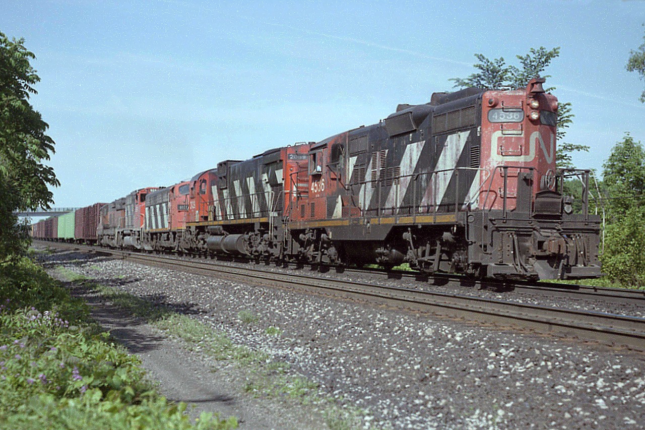 I was sitting out at the end of Howard Rd in Aldershot when this eastbound came thundering thru. I should mention that this was once a great place to park and wait; as the dead end road had a little bit of grassy area alongside the tracks. However, the construction of the third rail (for GO) killed this spot and now what there is left is off limits.
Had the 4x5 Graphic in hand this day, and almost didn't get this shot away due to a bit of fumbling, which sometimes happened when I was in a rush.  Interesting assortment of power; CN GP9 #4536 long hood forward, followed by C-630M #2039, F7A #9175, GP40-2(W) # 9584 and B&LE SD9 #825 trailing.
That is Lemonville Rd bridge on the left background.