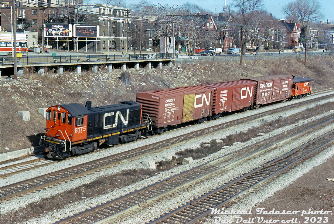 Sunnyside Just passing through: CN 8175, an MLW S7, heads westbound on the Oakville Sub through Sunnyside with a short local in tow. Two 40' boxcars follow: one an 8' door car (yellow doors signified newsprint service) the other a rebuilt 9' door car, plus a Southern 50' boxcar and one of CN's distinctive transfer cabooses. An eastbound TTC CLRV streetcar can be seen above on King Street West.Michael Tedesco photo, Dan Dell'Unto collection slide.