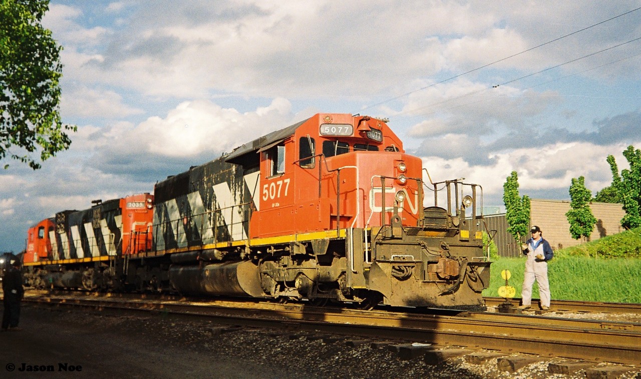 CN 421 with SD40 5077 and C-630 2035 are preparing to couple to their loaded frame cars brought-up to the Kitchener Yard from the Huron Park Spur by the 15:30 Kitchener Job. From here they would resume their trip westward to London. 

In less than a year, CN 2035 would be acquired by RailTex for their new Cape Breton & Central Nova Scotia Railway (CBNS) operation. Then shortly after in winter 1994, the C-630 would find itself back rolling over a portion of the Guelph Subdivision at Stratford as it attempted to assist fellow RailTex company the Goderich-Exeter Railway during a motive power crunch.