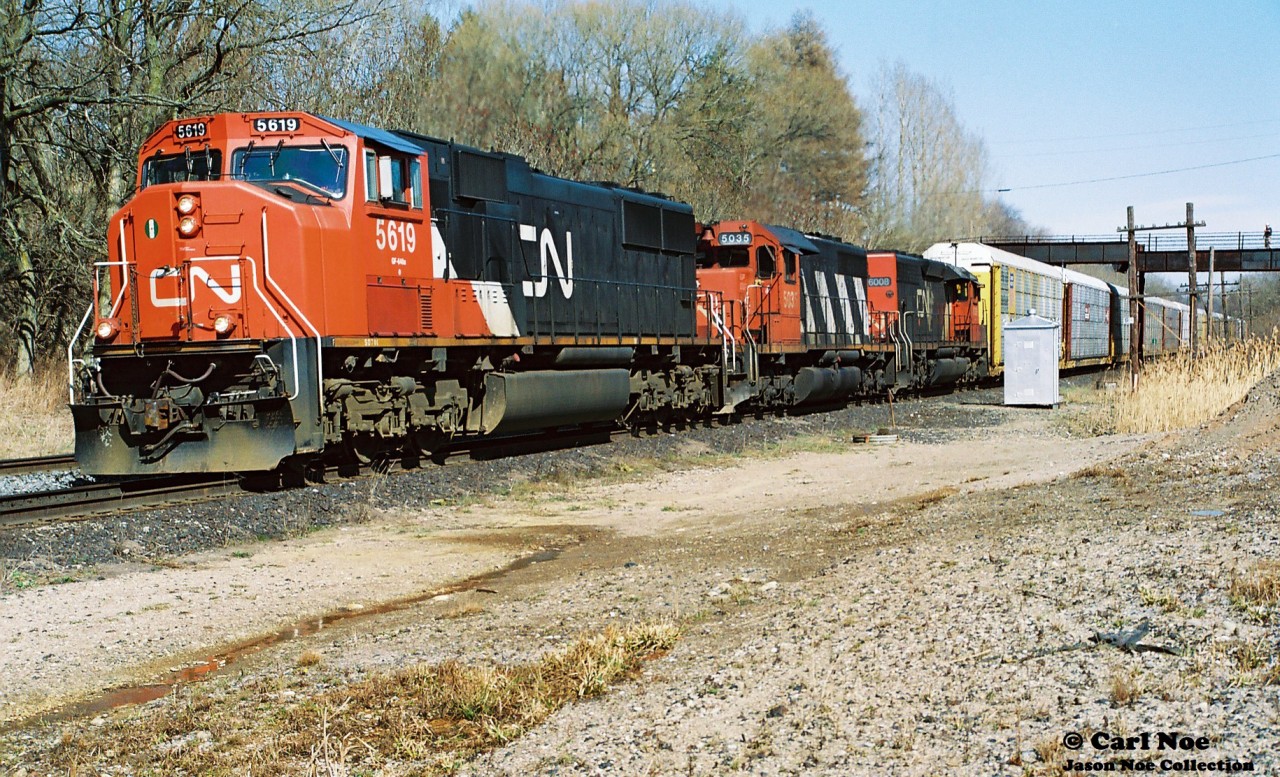 A CN westbound with CN SD75I 5619, SD40 5035 and SD40-2Q 6008 are viewed grinding to the top of the Dundas Subdivision grade at Copetown, Ontario during spring 1999.