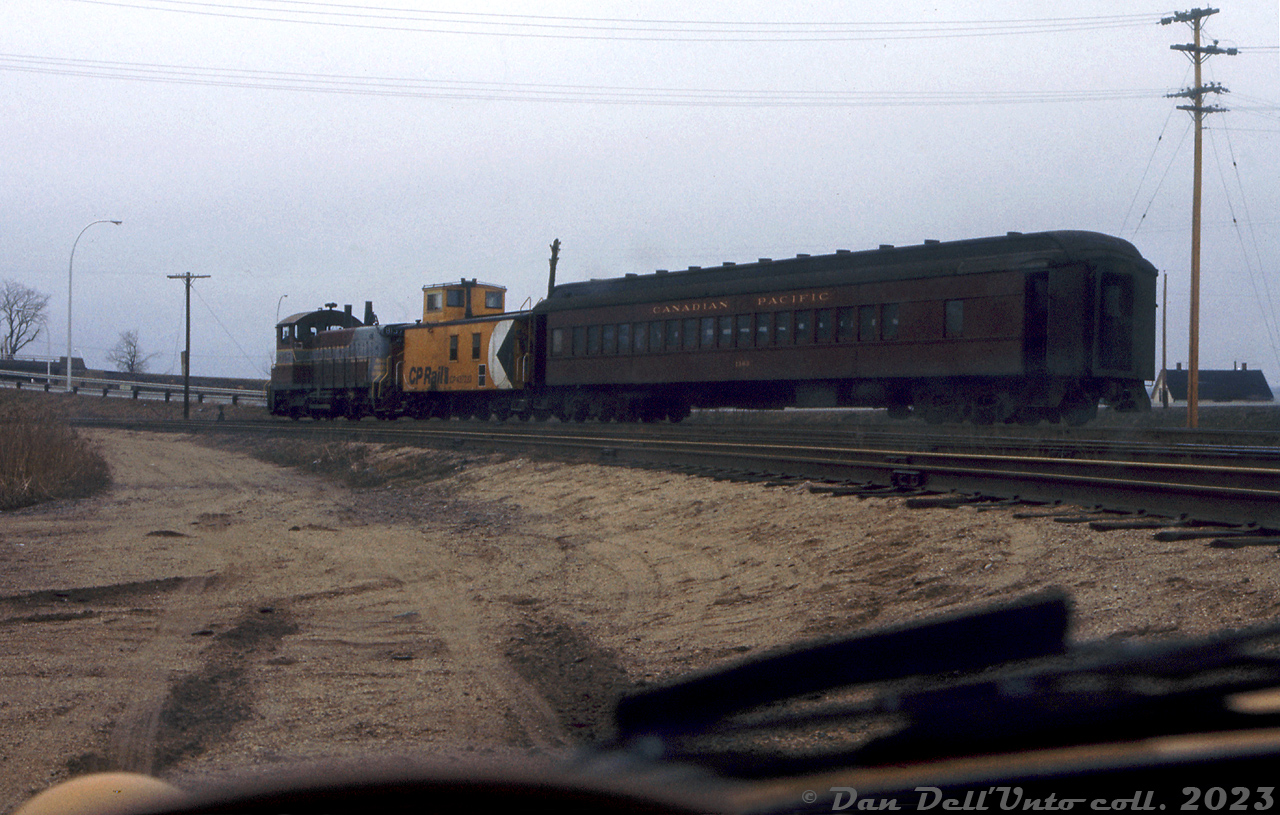 Viewed from the unknown photographer's seat of a yellow Opel GT during an April 1975 trip railfanning Canadian Pacific's Dominion Atlantic Railway, CP SW1200RS 8137 is in charge of today's Truro-Windsor mixed train #22, seen here at Windsor NS coupled to its wooden 437xxx-series van and steel heavyweight coach 1303. The mixed may have dropped their freight at the yard, and be waiting to head to the station nearby.

Just like how the 8160-8162 were longtime assigned units on the GRR/LE&N, the 8130-series SW1200RS units were typical power assigned to the DAR, sometimes travelling to Montreal for major work. In later years, rebuilt 1200-series units would handle duties with other 8100's. 

At the time of this photo, DAR ran a mixed train from Truro to Windsor (#22) in the morning, and back from Windsor to Truro (#21) in the afternoon. This was the last mixed train operating on Canadian Paccific, and was likely one of the last uses of heavywight coaches in revenue service on the system. Regularly assigned at this time was coach 1303, a heavyweight first class coach originally built in 1929. 

In June the 1303 it was replaced by another heavyweight coach in mixed service (1720, that was used until the end, and featured bus-style seats. 1303 was then donated to the National Museum of Science & Technology (becoming their "Micmac"), eventually going to the BC chapter of the NHRS out west, and has since been since sold to US orgianization Heber Valley with most of the collection.

Original photographer unknown, Dan Dell'Unto collection slide.