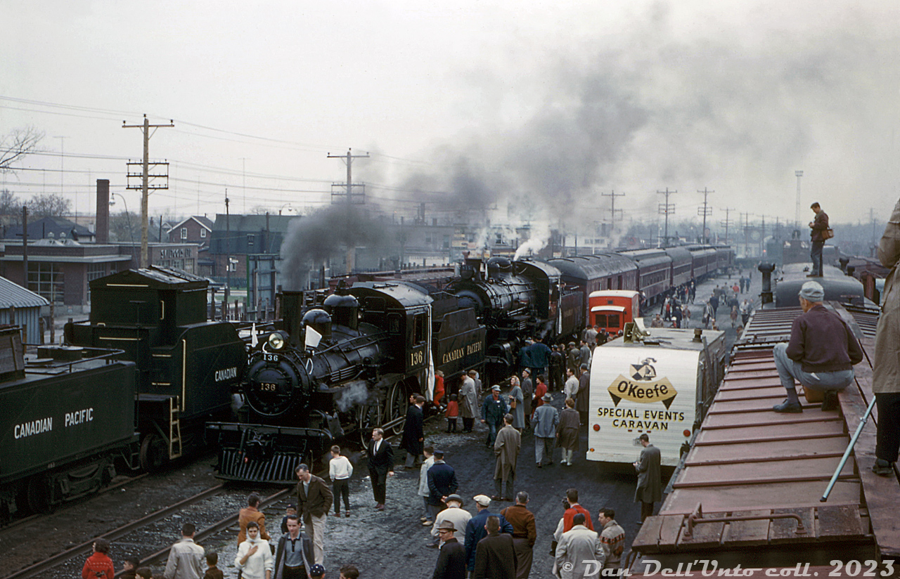 On Saturday, April 30th 1960, the day before the famed Canadian Pacific Tripleheader, a doubleheader trip was run on the Galt Sub from Toronto to Cooksville and back (fully within yard limits) using CPR 4-4-0 136 and 4-6-0 815. The two steam engines and their train of heavyweight passenger cars are seen inside Lambton Yard posed for photos along the north end of the yard bordering St. Clair Avenue West around Jane St. underpass, in the West Toronto "Junction" neighbourhood. Railfans, photographers and attendees crowd the yard between tracks filled with old "OCS" work equipment (including old boxcars, passenger cars, and old steam engine tenders converted for water service), with some taking it upon themselves to climb on top for a better view. The O'Keefe Brewing "Special Events Caravan" is even in attendance!

Original photographer unknown, Dan Dell'Unto collection slide. 

Another view of the train, being serviced at the shops: http://www.railpictures.ca/?attachment_id=41815

The tripleheader with 1057 the next day: http://www.railpictures.ca/?attachment_id=48680