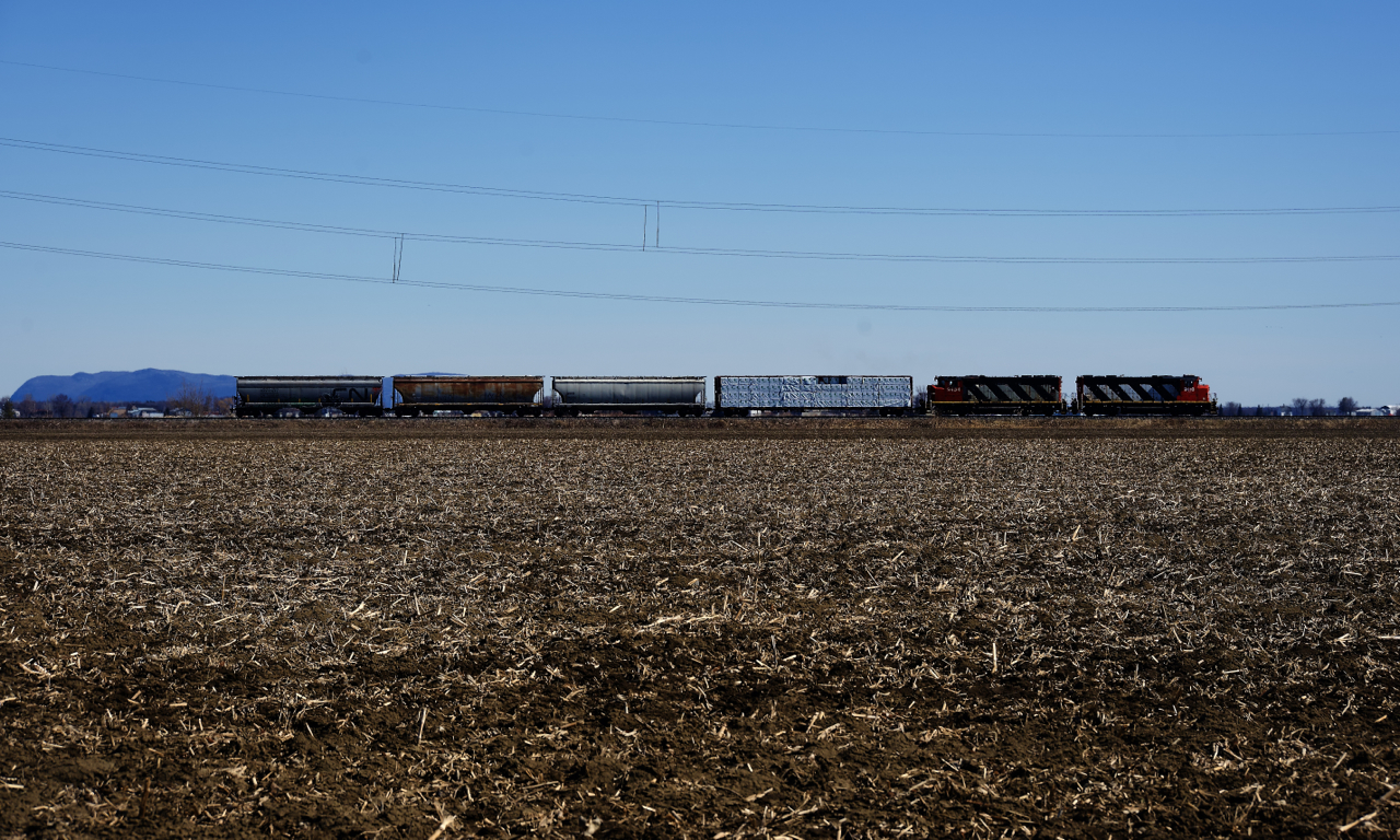 CN 522 has one car for BarretteWood and three cars for Nova Grain as it passes a barren field on the approach to Saint-Jean-sur-Richelieu.