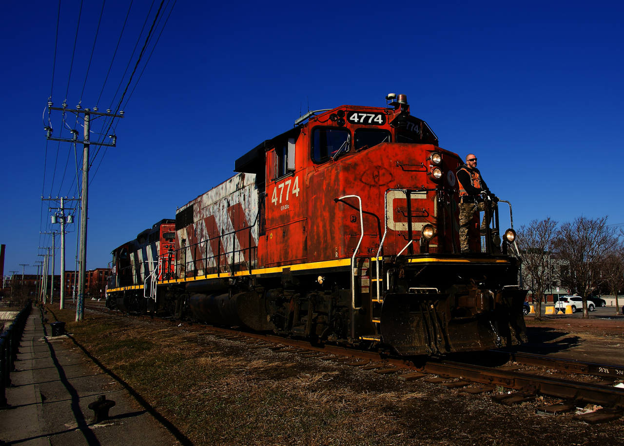CN 4774 & CN 4115 are heading east along the East Side Canal Bank Spur to pick up seven grain empties at Ardent Mills. After bringing those cars to Pointe St-Charles Yard, they will return here with seven loads.