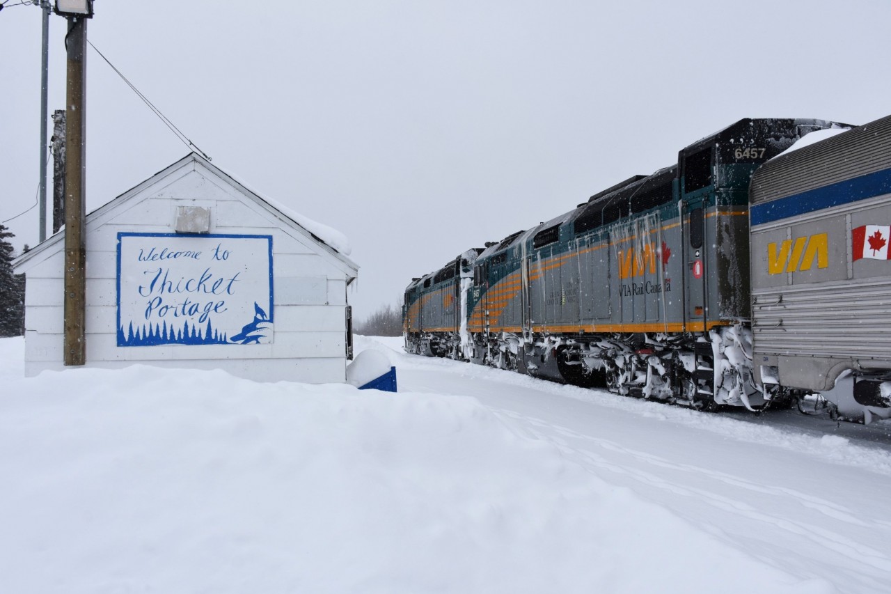 Other than a couple of locals off-loading supplies from the baggage car, there was no one else on the platform at Thicket Portage, MB but me on this cold and snowy morning. The weather has changed dramatically from the day before when I was in Churchill, MB where it was blistering cold, but beautifully sunny with not a cloud in the sky. This snowfall would get heavier as the day went on and eventually leave over a foot of fresh stuff by the time it was over. 
The community was originally known as Franklin Portage after the Franklin expedition. It is one of the portages in the route used to connect the Nelson River system with Wintering Lake. The community is located on the Hudson Bay Railway. 
Thicket Portage is 48 km south of Thompson and 256 km northeast of The Pas. The railway provides the only all-year surface transportation linkage to the outside. A winter road is established for six to eight weeks every year.