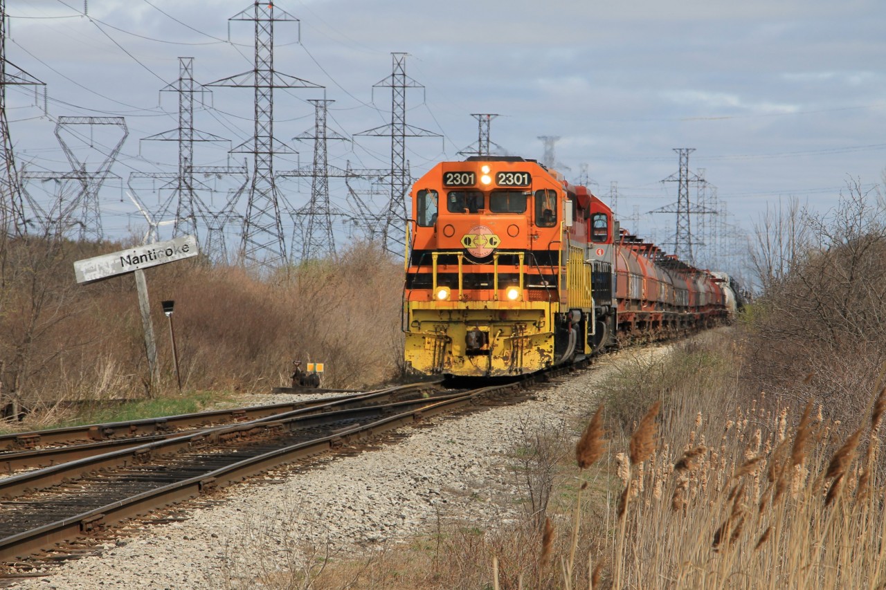 The SOR Garnet Yard day job with QGCY 2301 and RLK 4095 are trailing a block of coil cars for Stelco and a block of tanks for Imperial Oil has slowly made its way south from Garnet Yard and is stopped at Mile 0.00 Hagersville Sub. at Nanticoke the junction with the Stelco Spur and Hydro Spur. The crew is waiting the arrival of GEXR 2303 (Imperial Oil Job) which is behind the photographer running light northbound on the Hydro Spur. The crew has lined the switch for the Stelco Spur, after a job briefing between crews QCRY 2301 and RLK 4095 will head south with the block of coil cars on the Stelco Spur, having cut-off the block of tanks to be lifted by GEXR 2303.