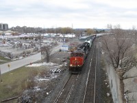 CN 5286 and an unknown unit (maybe an IC) along with a new GO Transit unit in tow lead an eastbound up the south track of the Halton Sub. at Mile 48.9 about to pass under Plains Road. CAPBRICK was a busy spot then and the place to go for stone products, today the property sits empty but the sign remains. Sightline concerns for the new westward signals at Burlington West will be addressed starting with the removal of trees on the north side.