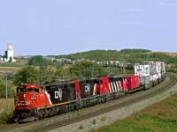 Westbound containers curve through the Arrow River Valley in western Manitoba. The abandoned CPR Miniota branch ran parallel to the CN through here and the elevator is on the CPR RofW alignment. 