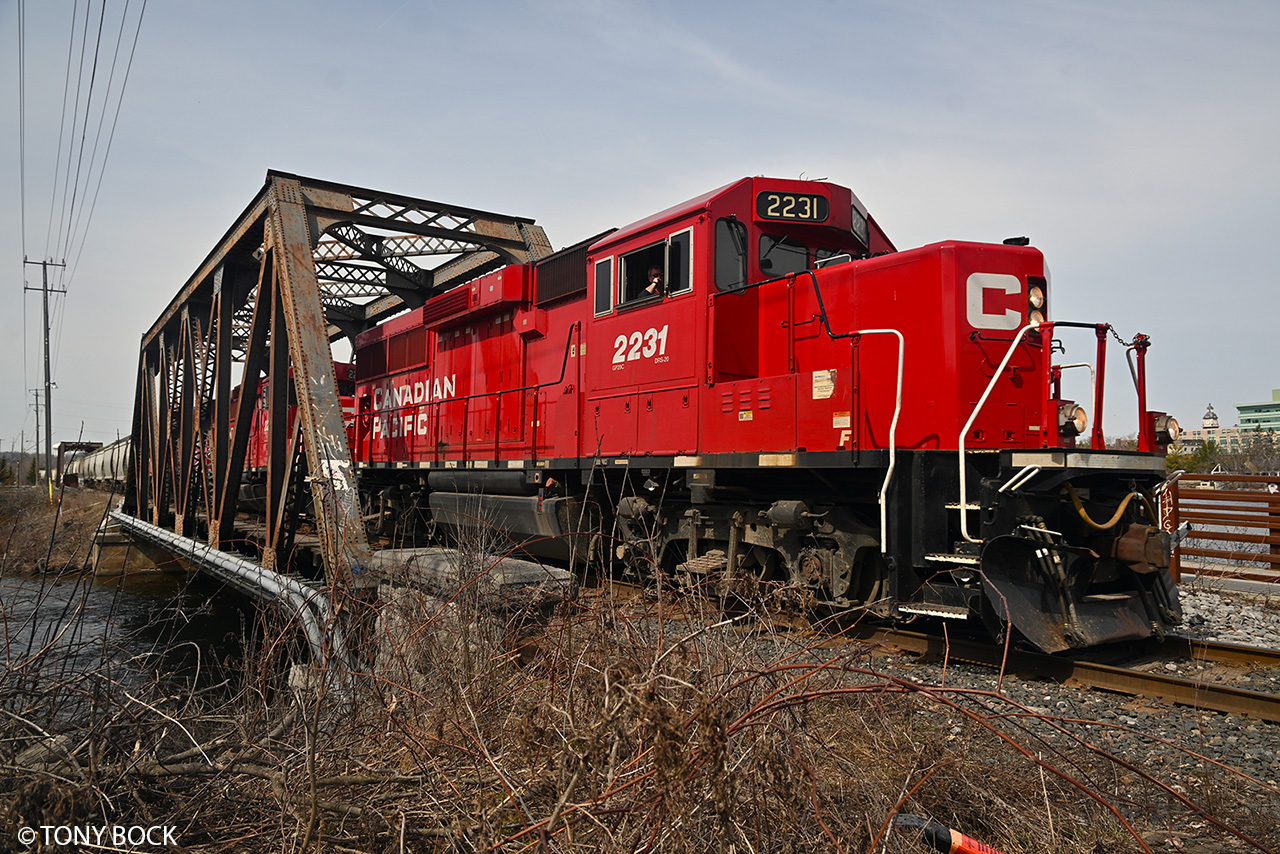 On its way to Havelock and Blue Mountain to serve the nepheline syenite mine, CP train T08 crosses the Otonabee River bridge (built 1913) in downtown Peterborough, on April 11th, 2023. Today's long train is powered by three locomotives, led by GP20C-ECO 2231.