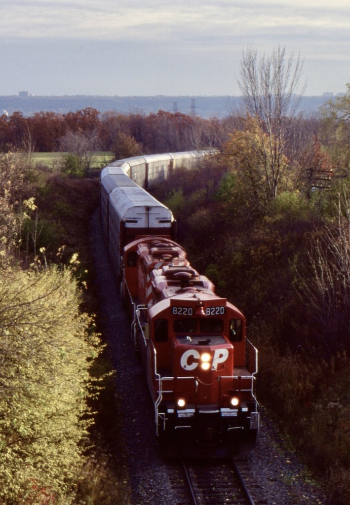 The gradual retirement of CP's RS18's and C424's pushed the GP9U's to take over many more assignments. At this time the "Ham Turn" was kind of an interesting job. The old TH&B Aberdeen yard had recently been almost cut in half and the power that was typically kept there like the MLW's, was moved to Kinnear. The old TH7B car shop at the time was being used for fixing auto racks, most destined for the Toyota plant in Cambridge. Unfortunately the old shop was in bad shape and future developments as far as the steel transfer facility would force its demolition. At this time the shop was still active, and this days "Ham Turn" has a good cut of auto racks from there heading up the Niagara Escarpment towards Cambridge, with a pair of GP9U's for power. The city of Hamilton can be seen in the background. The "Ham Turn" would still see another decade before being abolished along with a number of other trains.