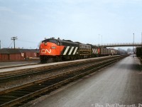 The new image of CN: GMD FP9 6525 and CLC CPA16-5 6704, both in fresh zebra stripes and sporting the new CN "noodle" logo, bracket F9B 6621 in the older green, black and yellow livery as they pull into the station at Brockville with a westbound passenger train. The new modern logo and livery (first unveiled in 1961) was still in its infancy at the time of this photo, evident by the passenger and head-end baggage and express cars all still sporting the older paint scheme (if one looks closely, there appears to be a maroon private car on the tail end).
<br><br>
In the background are the nearby CP freight sheds, with 40' boxcars spotted at the loading platforms.
<br><br>
<i>Original photographer unknown (slide labeled "Stewart" on the back), Dan Dell'Unto collection slide.</i>