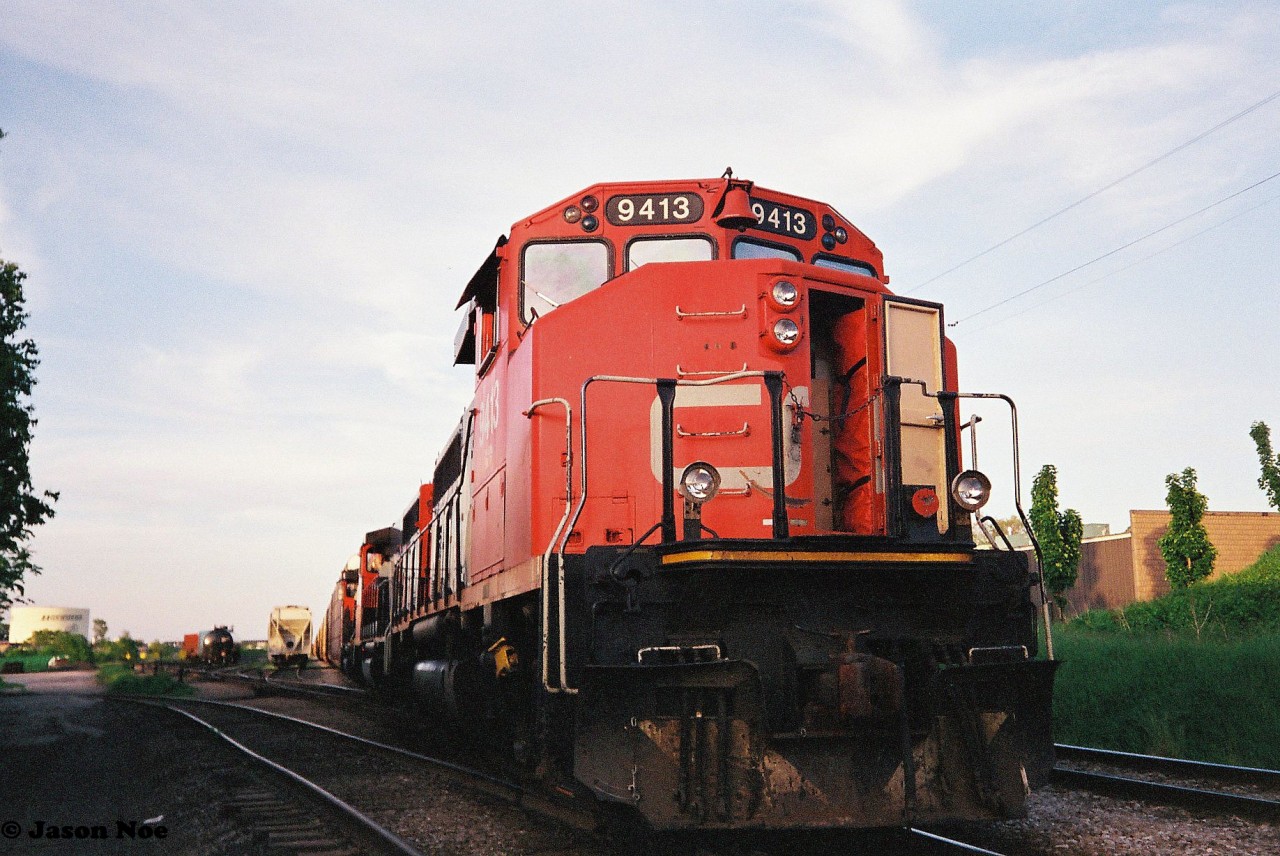 On a summer evening in 1993, CN 413 with lead unit 9413 west, was sent down the Guelph Subdivision to Sarnia, Ontario. Train 413 was a very high priority finished vehicle train that had operated between Oshawa and Sarnia where the auto racks made their connection to the US. On this evening, the train had to take the siding at Kitchener to meet the joint VIA Rail/ Amtrak International before proceeding west. Here, with the crew at the popular Dairy Queen, CN 9413 is viewed at the Kitchener yard near Lancaster Street.