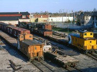 A view of the Canadian Pacific Railway 'Upper Yard' at Guelph taken from the Heffernan Street footbridge shows various pieces of MoW service rolling stock behind <a href=http://www.railpictures.ca/?attachment_id=29496>the unique freight shed</a> that served the Royal City until a <a href=https://guelph.pastperfectonline.com/photo/F4743B03-ACE8-4F08-99E7-812312363734>fire in May 1991.</a>  American crane CPR 414230 can be seen just above caboose 434816, which had been used a few months earlier during February as a pile driver (note parts on car behind) to repair timbers on the wooden trestle <a href=http://www.railpictures.ca/?attachment_id=35155>at mile 29.75 Goderich Sub.</a>  Note removed bridge timbers in gondola.  Per Bruce Lowe images taken during the bridge work, all equipment other than what is on the near track has remained in the yard since the winter months.<br><br><i>Keith Hansen Photo, James Hull Collection.</i>