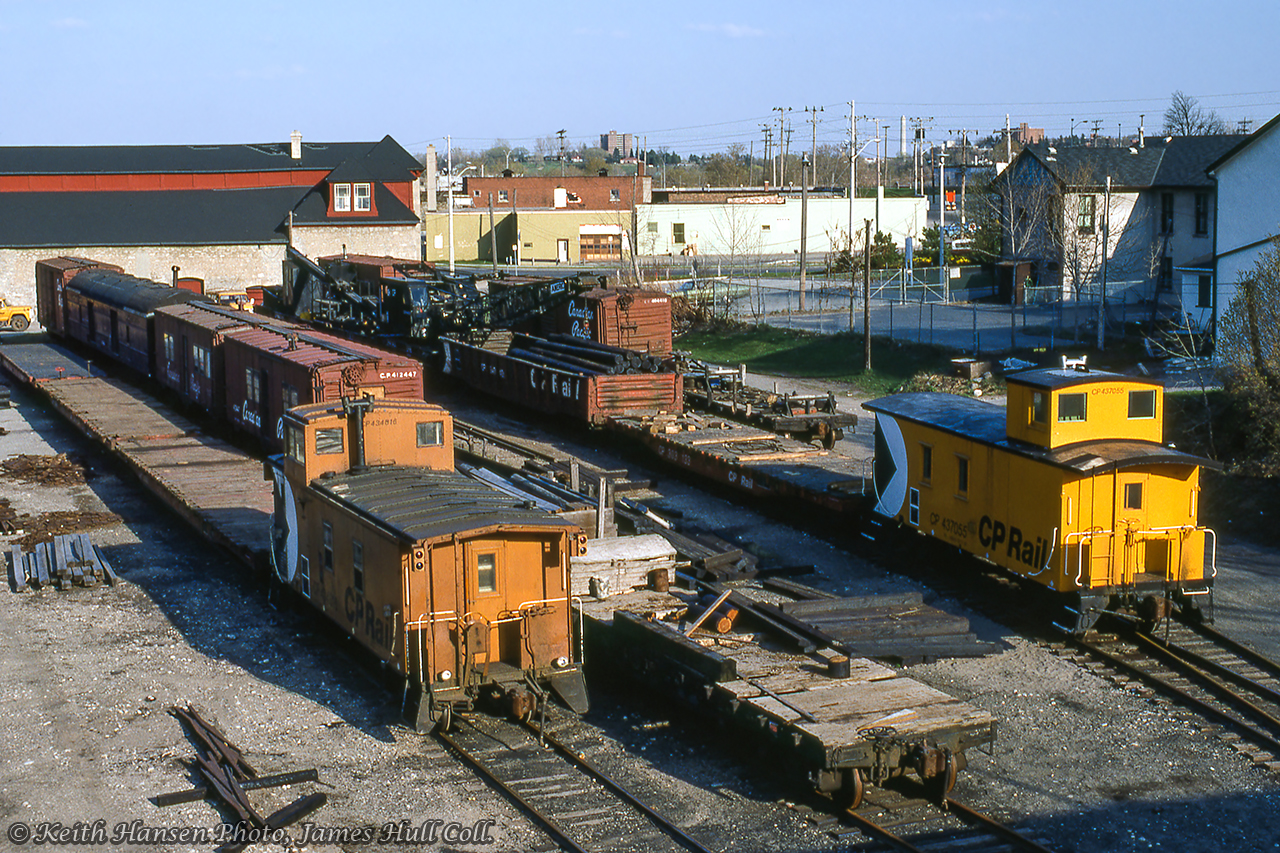 A view of the Canadian Pacific Railway 'Upper Yard' at Guelph taken from the Heffernan Street footbridge shows various pieces of MoW service rolling stock behind the unique freight shed that served the Royal City until a fire in May 1991.  American crane CPR 414230 can be seen just above caboose 434816, which had been used a few months earlier during February as a pile driver (note parts on car behind) to repair timbers on the wooden trestle at mile 29.75 Goderich Sub.  Note removed bridge timbers in gondola.  Per Bruce Lowe images taken during the bridge work, all equipment other than what is on the near track has remained in the yard since the winter months.Keith Hansen Photo, James Hull Collection.