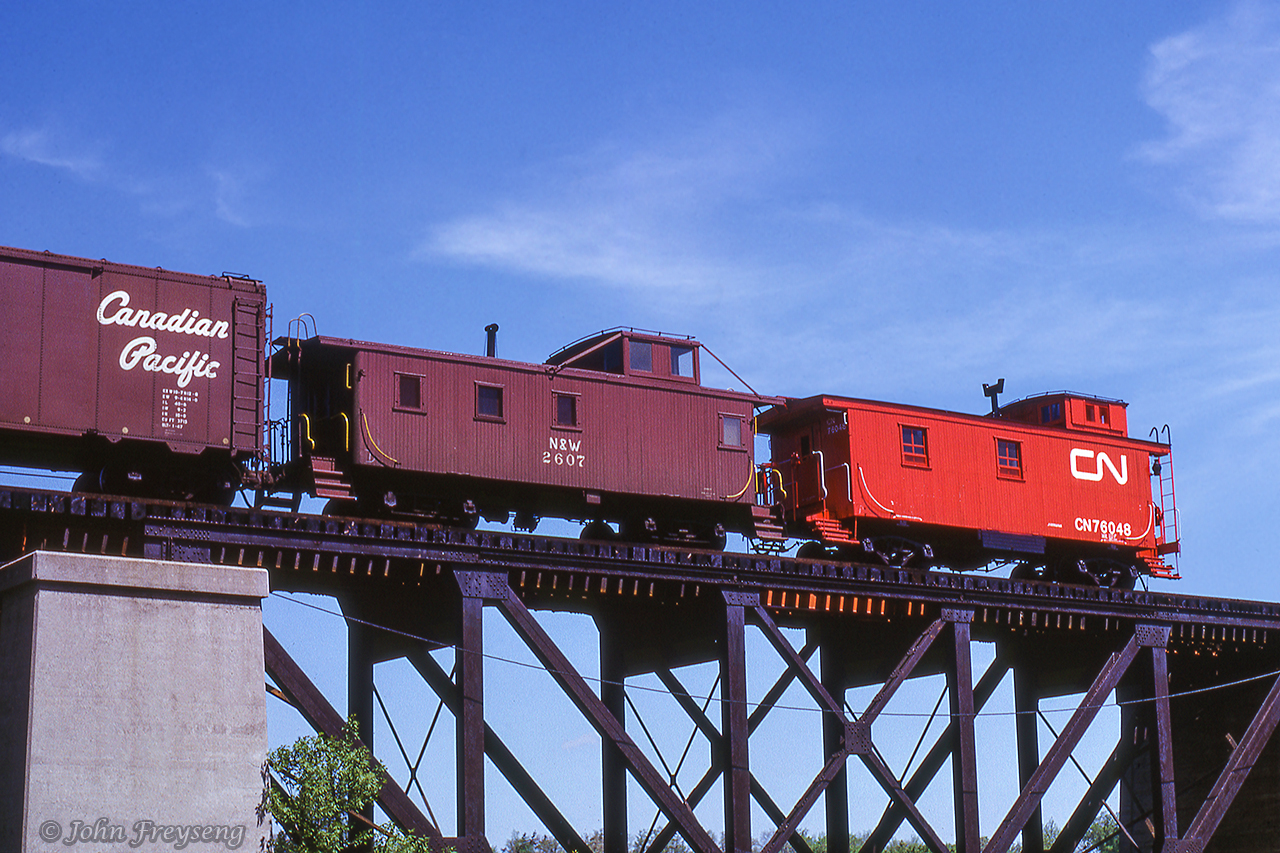 A surprise on the tail end of extra 3875 west as it crosses the Grand River at Cayuga, N&W caboose 2607 appears just ahead of CN van 76048.Scan and editing by Jacob Patterson.