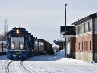 Three different railways are represented in this photo at The Pas, MB. on this blistering cold March 16, 2023 morning. <BR>
At the left of the frame is VIA Rail's #691 consist of stainless steel Budd built passenger equipment waiting to return to Churchill, on the main in front of the station is KRC's (Keewatin Railway Co.) #291 The Pukatawagan Mixed with classic ex-VIA, exx-CN baggage car and coach loading up with passengers, baggage, and supplies, and, the red brick building to the right is HBR's (Hudson Bay Railway) Maintenance building at 313 Hazelwood Ave. The Pas. <br>
The only remnants identifying this location as a former Canadian National northern Manitoba hub are three old zebra striped locomotives (renumbered for HBR) sitting stored out of sight in the distant yard near the roundhouse/diesel shop facility.