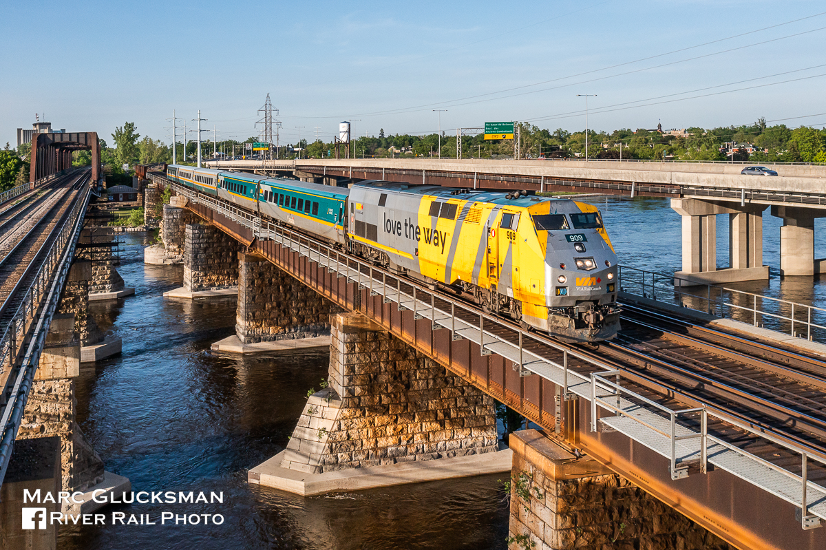 la voie qu'on aime. VIA Rail Canada 909 (P42DC/EPA-42a) led train 669 (Montreal, QC-Toronto, ON) on the afternoon of May 29, 2023, seen crossing the Sainte-Anne-de-Bellevue Canal approaching Bellevue Island, Montreal, Quebec. The 5 car-LRC train is lead by a P42 that is one that VIA wrapped in this advertising scheme, with English (love the way) on one side and French (la voie qu'on aime) on the other.