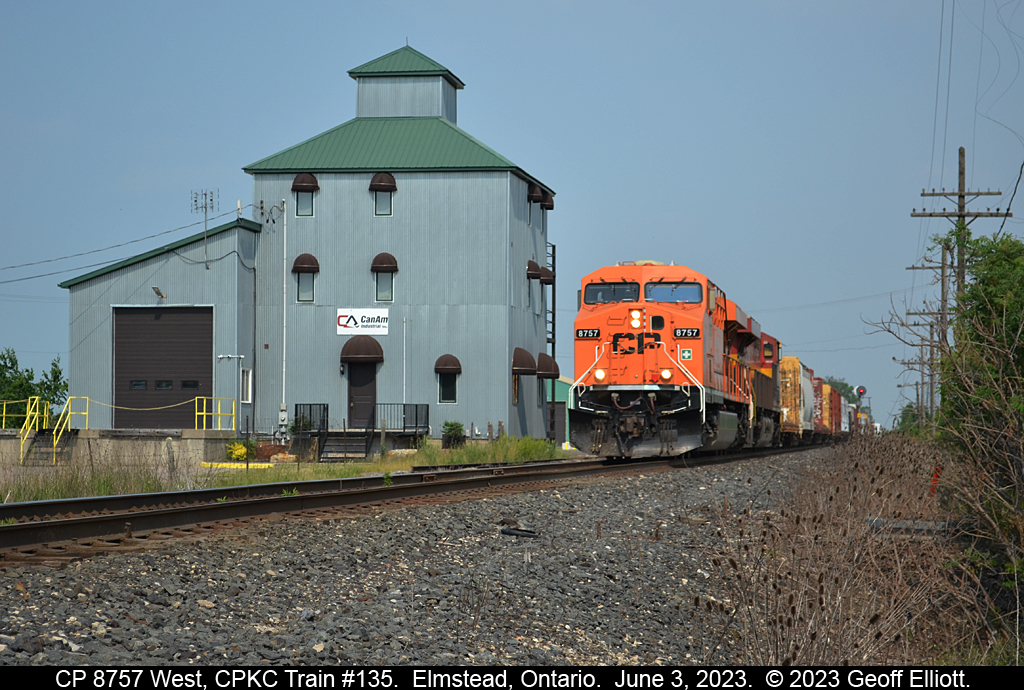 CPKC Train #135, formerly known as #231 when it arrived in London, passes the old, re-purposed, "Ruggabers" mill in Elmstead, Ontario, on June 3, 2023.  Train #135 is huge today and has CP 8757, the Every Child Matters unit, on point and a KCS trailing as it rolls by MP 101 of the CPKC Windsor Subdivision.