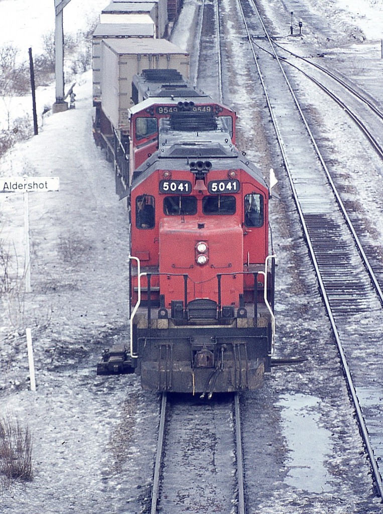 Back before all the modern GO/VIA facilities were built here, the view looking east off of the Waterdown Rd bridge in Aldershot was of a long yard on the north side. This image shows CN 5041 and 9459 pulling out onto the north main with some TOFC up front, general freight in behind.  It has been quite a few years since we have seen trailers on flat cars over either CN or CP.
The SD-40 5041 went off roster in 1999 and was rebuilt to a SD40-2 for BNSF according to the Cdn Trackside Guide.
As for the wooden Aldershot namesign.........it SHOULD be in my garage, but, alas, it isn't.
