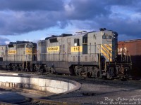 Bellequip GP7 110 and GP9 130 sit dodging the shadows by the diesel shop turntable inside Canadian Pacific's Toronto (Agincourt) Yard. At the time, both units were part of a large group of former Quebec, North Shore & Labrador (QNS&L) GP7/GP9 units that were leased by CP in the early-mid 1970's, initially through a group called "Bellequip" (apparently run by some CP management types on the side). They later sold their lease fleet to Us-based Precision National Corp (with all units later relettered PNC by CP). By the mid-1970's traffic lull, the old Geeps all came off-lease, and most ended up purchased by the Chicago & North Western.
<br><br>
Apparently QNS&L embarked on a rebuild/upgrade program for their GP7's at one time, so 110 is now a GP9 equivalent (larger main generator retrofit? note the extra louvres/vents on the hood doors. Information on this program is hard to find).
<br><br>
<i>Ray Sabo photo, Dan Dell'Unto collection slide.</i>
