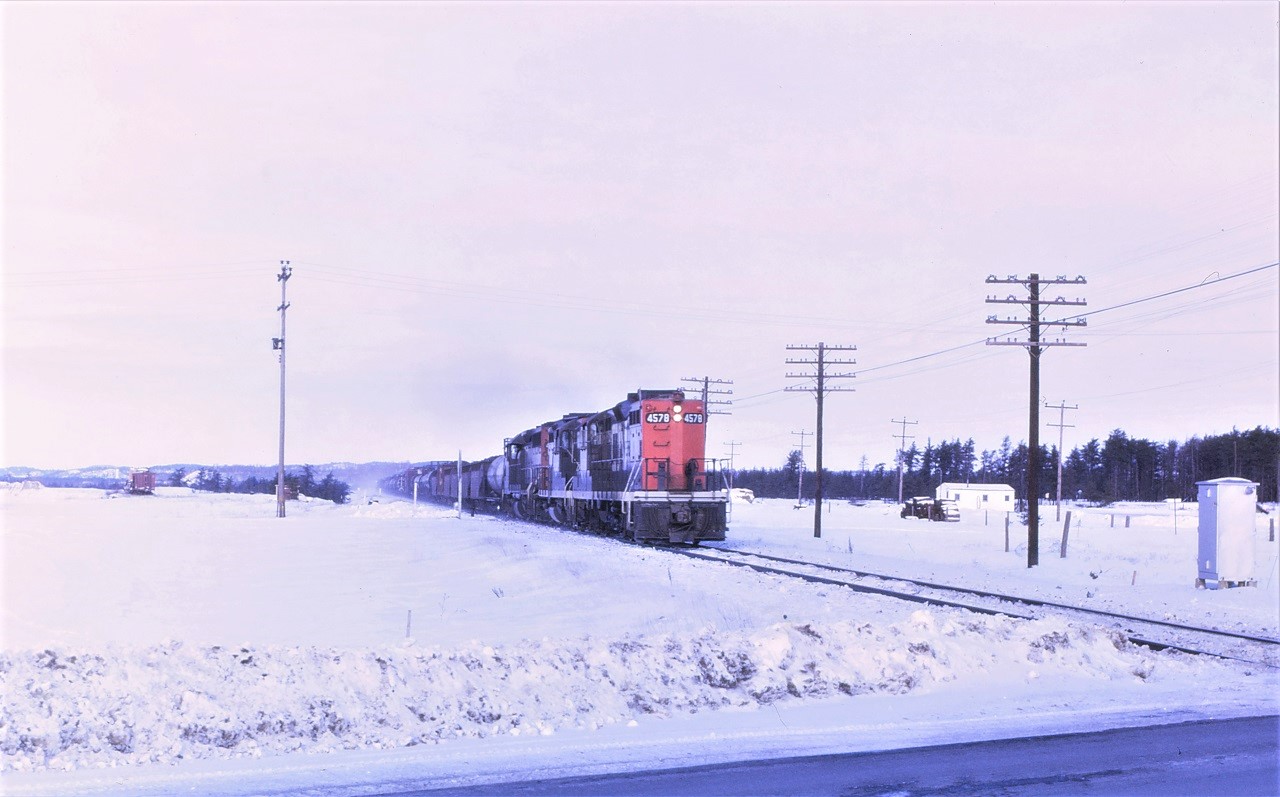 CN train 474 races south over the south switch at Suez, Ontario on the day after Christmas 1969.  The first dozen or so cars will be set off at Sudbury.  Power for the train is 4578, western lines 4248, and 4016.