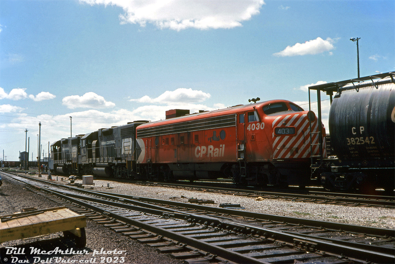 CP FP7 4030 trails Penn Central GP38-2's 8077 and 8061 in a mixed power lashup, moving around the east end of CP's Toronto Yard (aka Agincourt Yard). The train is likely the PC-CP "Kinnear" (BUCP / CPBU) or possibly the CP-TH&B "Starlight" (PC power sometimes appears on it). By this time, the PC Geeps were owned by newly formed Conrail (created two months earlier on April 1st 1976), but not yet patched or repainted.CP 4030 was part of the first order of locomotives placed with GMD for their new locomotive assembly plant in London, Ontario (CP FP7's 4028-4037, built 1950) and the oldest CP F-unit at this point, surviving trade-ins and wrecks that took out older sisters 4028 and 4029. She continued to run until the majority of CP's remaining F-units were retired from freight service in 1982.Bill McArthur photo, Dan Dell'Unto collection slide.