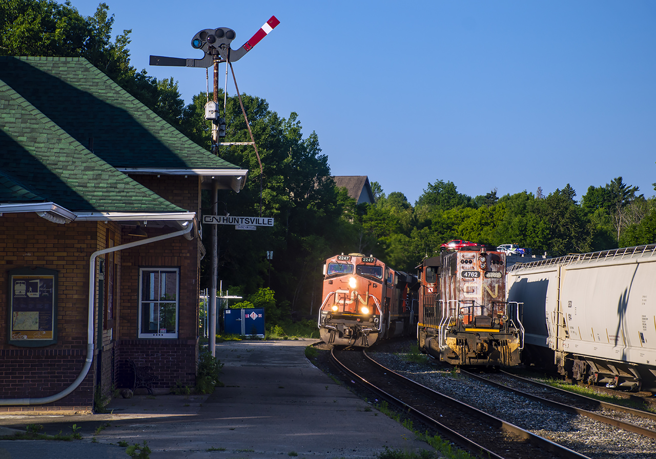 Beneath the order boards atop Huntsville's 1924 CN station, Mac Yard - North Bay freight A451 crawls to a stop to make a setoff of local traffic and ballast cars.  Local L595, powered this day by CN 4762, will begin breaking up the setoff shortly after 451's departure, before servicing nearby industries.