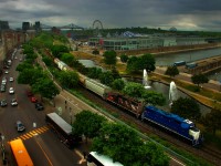 As seen from a tower that is part of the Pointe-à-Callière Museum, CN 500 is seen leaving the port as light rain falls. CN 4903 & CN 4731 is the power on this 12-car train.