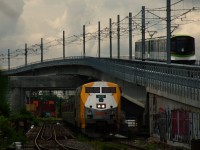 In a scene that would be unrecognizable to railfans who haven't been to Wellington Tower in Montreal recently, VIA 60 is passing Wellington Tower (completely blocked off by the REM right of way at right) as an REM test train passes overhead. In the distance are fairly new signals located at the location formerly known as Cape.