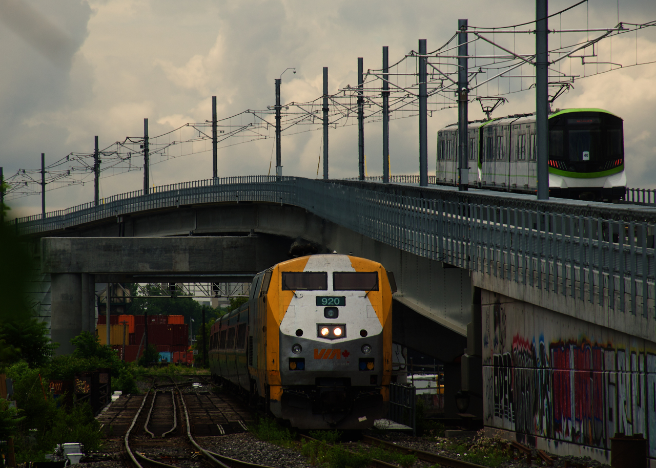 In a scene that would be unrecognizable to railfans who haven't been to Wellington Tower in Montreal recently, VIA 60 is passing Wellington Tower (completely blocked off by the REM right of way at right) as an REM test train passes overhead. In the distance are fairly new signals located at the location formerly known as Cape.