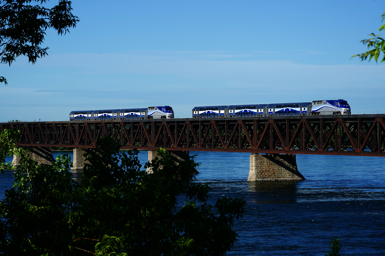 Deadhead and revenue moves are meeting over the St. Lawrence River during the morning rush hour. At left EXO 1328 leads EXO 76 towards the island of Montreal, while EXO 1320 at right pushes EXO H73 towards the South Shore. It will provide the consist for EXO 80, the 0825 departure from Candiac for Montreal.