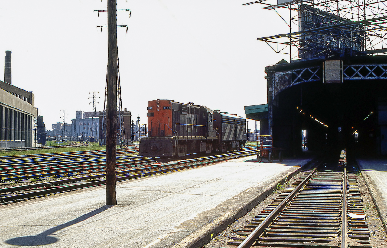 The sun is high in Toronto in June 1970. CN 3106 and an unknown CN MLW FPB-4 are seen near Toronto Union Station.