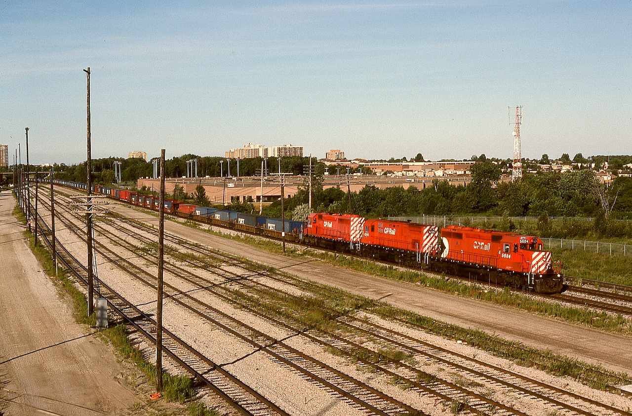 Viewed from the Markham Road overpass above SNS Toronto Yard, CP 5864 + 4246 + 5590 are bringing a westward container train into the yard in Agincourt at 1908 EDT on an extremely warm Wednesday 1994-07-13.