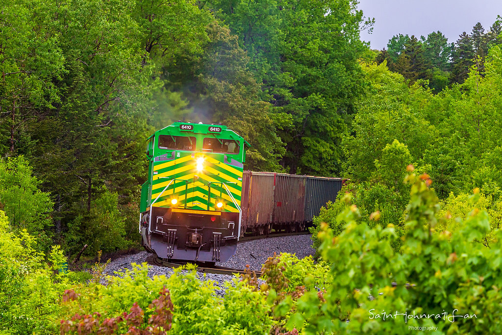 New Brunswick Southern Railway 6410 leads train 120 as they come out of the woods and around the bend at Grand Bay, New Brunswick. Nice to have the green scene that the summer brings. Rain for the last two days really brings out the tree colors, and the green ponies are a nice touch.