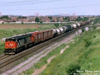 A warm July afternoon in 1993 finds CN HR616 2118 and an M636 rolling train #305 through the interlocking plant at Snider on the York Sub, hammering the diamond with CN's Newmarket Subdivision before taking the inbound leads into the sprawling MacMillan Yard nearby. The twenty 251-powered 2100-series Bombardier HR616's were CN's last dabble into 6-axle Alco/MLW power, and the first CN units to sport the new "Draper Taper" cowl hoods. Future orders would go to GMD (SD50F/SD60F) and later GE (C40-8M) however, and both would outlive the HR616's.
<br><br>
<i>Karl Bury photo, Dan Dell'Unto collection slide.</i>