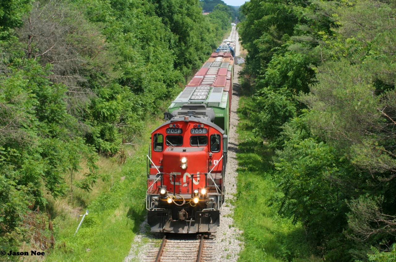 CN L568 is viewed just west of the town of New Hamburg, Ontario as it heads towards Stratford on the CN Guelph Subdivision with CN 7058 and a former GMTX GP38-2 mid-train on a summer afternoon.