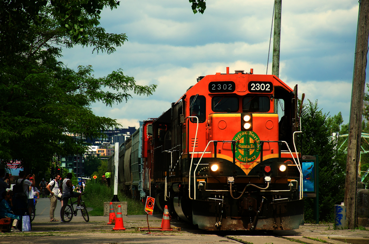 BNSF 2302 is leading CN 500 as it shoves grain loads past the Atwater market. Behind the power is a GTW van, recently transferred to Pointe St-Charles Yard.