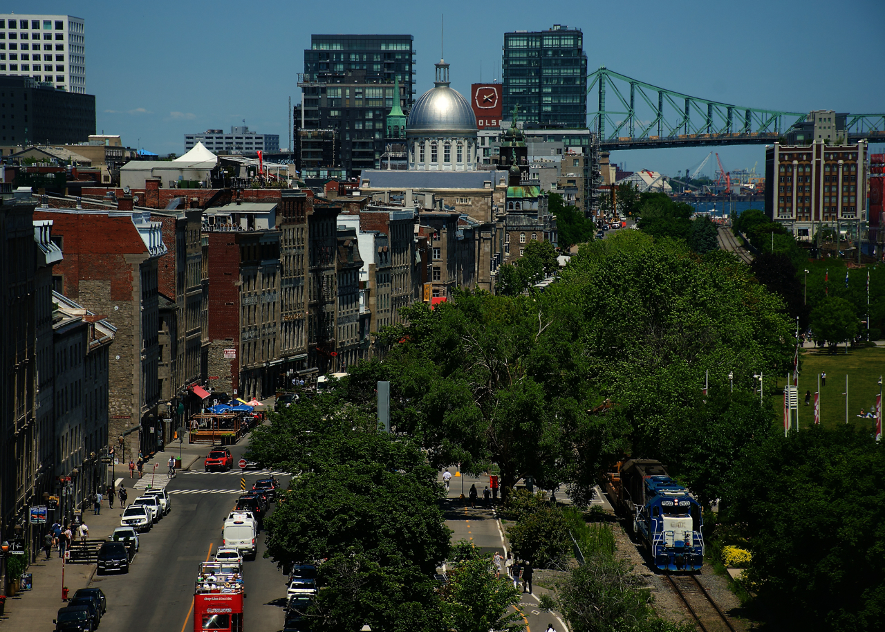 CN 500 is leaving the Port of Montreal with well cars, as seen from a tower that is part of Pointe-à-Callière museum.