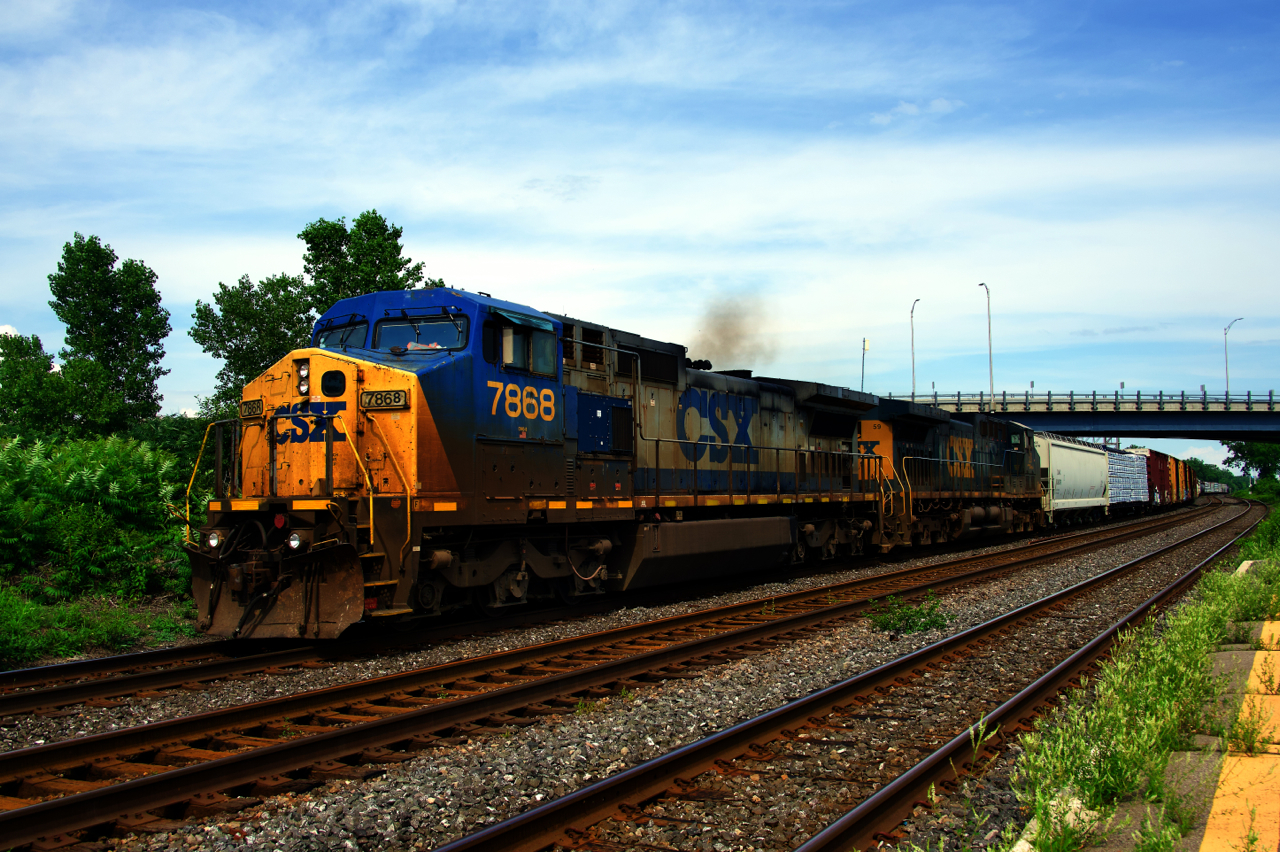 A short CN 327 has a Dash8 still in YN2 paint leading as it passes through Dorval with CSXT 59 trailing.