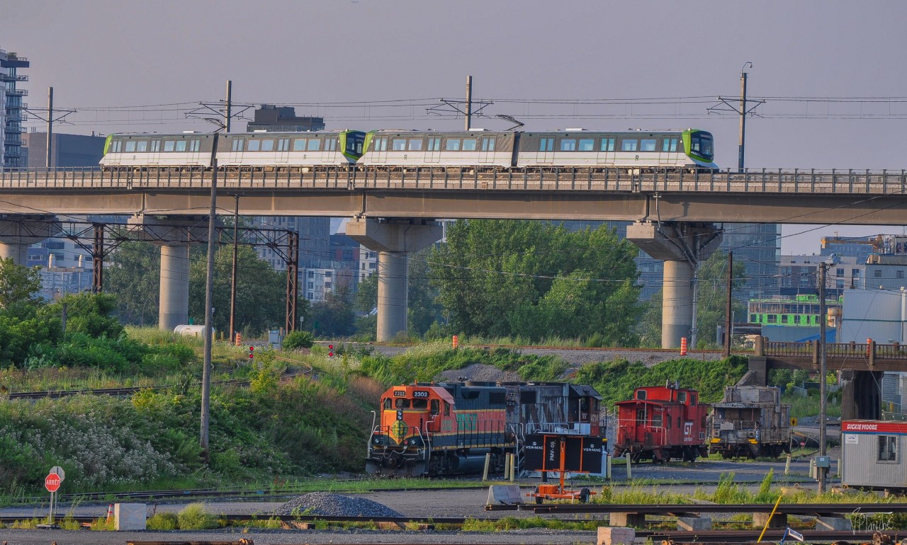 On July 17, 2023, CN 596 sits in CN's PSC yard. A REM train, which opens in a few days, passes over it towards Brossard.
