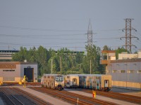 On July 17, 2023, several new EXO cars are parked in the PSC Maintenance Center (EXO side). We see a REM train heading towards Brossard crossing the Pointe-Saint-Charles sector.