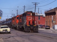 A one time only occasion, CN GP9s 4533, 4579 and RS18 3104 lead a unit acid train along Ferguson Avenue, destined to the TH&B interchange.  Per discussion with TH&B historian Lance Brown, this move is remembered by several TH&B pensioners, though the exact reason for the move cannot be recalled.  On arrival at the interchange, the train was lined straight into Kinnear, where the CN power cut off, grabbed their van off the tail, and proceeded back to the interchange and onto home rails.<br><br>Generally, these CIL acid trains had an all CP routing from Copper Cliff or Falconbride to Hamilton, where the TH&B would take the trains for delivery to Niagara Falls or Port Maitland.  Some of these moves can be seen below.<br><a href=http://www.railpictures.ca/?attachment_id=17272>Vinemount by Arnold Mooney, 1988</a><br><a href=http://www.railpictures.ca/?attachment_id=38939>Near Montrose by Reg Button, 1992</a><br><br><i>Bill McArthur Photo, Jacob Patterson Collection Slide.</i>