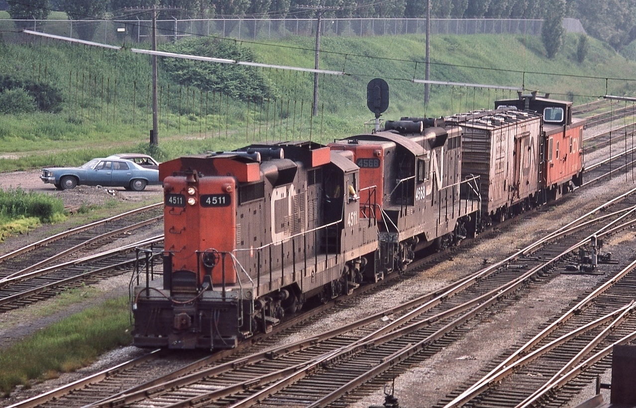Passing CN Cabin E mile 1.8 Oakville Sub, and on to the CN High Line, with a single reefer in tow, 


an eastbound CN transfer with GMD 1956 built GP9 CN  4511 and GMD 1957 built GP9  CN 4568


at TTR Bathurst Street, June 24 1979 Kodachrome by S.Danko


The CN High Line was the double track bypass that skirted south of the CN Spadina, CP John Street roundhouses & Union,


 rejoining the TTR station approach trackage east of the TTR Scott Street Tower.


More GM products in the background,


a circa 1975 Pontiac Laurentian sedan, and beyond that a Chevrolet Nova


sdfourty