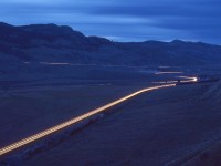 Westward from Kamloops Lake, CP and CN follow the Thompson River into a canyon, through Walhachin and onward to difficult-to-access Semlin (CP on the south side) and McAbee (CN on the north side).  Here is a late evening time exposure eastward view at the east end of CP Semlin on Sunday 1980-06-08, with headlight and ditchlight streaks of CP 5676 + 5651 westbound in the foreground, a CN westbound across the river, and the Trans Canada Highway distant above.  The total peaceful environment there made it a happy campsite for me.