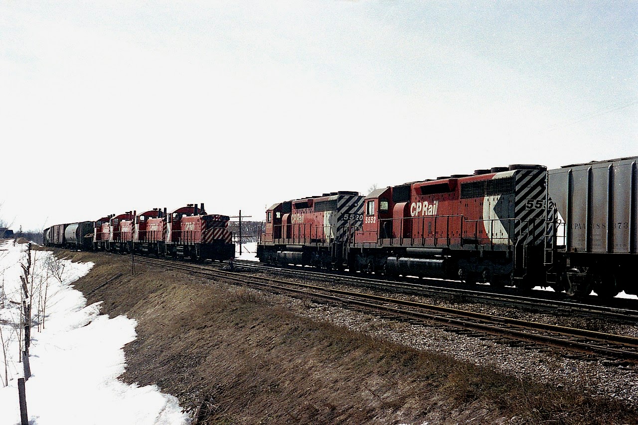 Freight meet on an early spring morning.  The snow is receding; a preview to the usual drabby looking ground once it is gone. At least the railroad activity is interesting.  Eastbound #50 with switchers CP 8144, 8145, 8164 and 8150 meets westward CP 5520 and 5552 just to the east of the Guelph Jct station. All locos now gone from the CP roster.