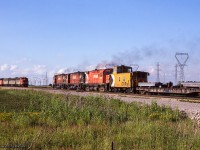 <b<A meeting of Nanticoke steel trains.</b> Three of Canadian Pacific's MLW C424s lead the loaded train north at CN Garnet, while an A-B-A set of Canadian National GMD F7s wait in the yard to proceed south to Stelco's Lake Erie Works with empties. This scene was captured as the operation was switched between CN and CP, which occurred every so many weeks.

<br><br>Per John Eull's article "The History of the Nanticoke Steel Trains - Part 2" in The Ontarian, CP's steel train was in its final year of operation before being 100% handled by CN. Prior to May 20, 1986, the train had operated Hamilton - Brantford - Waterford - Simcoe - Garnet - Nanticoke utilizing the TH&B Waterford Sub, LE&N Simcoe Sub, CN Cayuga and Hagersville Subs. A landslide at Cainsville during the evening of May 20 severed the line, which with a twelve million dollar price tag for repairs, resulted in the line being abandoned. A new route was established, operating Hamilton - Welland - Hagersville - Garnet - Nanticoke using the TH&B Welland Sub, and CN's CASO and Hagersville Subs.

<br><br>The shared operation of the train between CN and CP ceased on March 22, 1987, with CN operating the train until cancellation in the fall of 1989.

<br><br>More CP Steel Train:
<br>April 1983: <a href=http://www.railpictures.ca/?attachment_id=31711>Meet at Waterford</a>
<br>November 1983: <a href=http://www.railpictures.ca/?attachment_id=17321>Aberdeen Departure</a>
<br>March 1984: <a href=http://www.railpictures.ca/?attachment_id=50015>Eastbound at Jarvis</a>
<br>April 1984: <a href=http://www.railpictures.ca/?attachment_id=31712>Aberdeen Yard</a>
<br>April 1984: <a href=http://www.railpictures.ca/?attachment_id=47438>Westbound at Copetown</a>
<br>September 1984: <a href=http://www.railpictures.ca/?attachment_id=29385>Over the bridge at Waterford</a>
<br>August 1986: <a href=http://www.railpictures.ca/?attachment_id=4863>Southbound at Hagersville</a>
<br>September 1986: <a href=http://www.railpictures.ca/?attachment_id=52196>Northbound at Garnet</a>
<br>October 1986: <a href=http://www.railpictures.ca/?attachment_id=15934>Departing Hamilton</a>