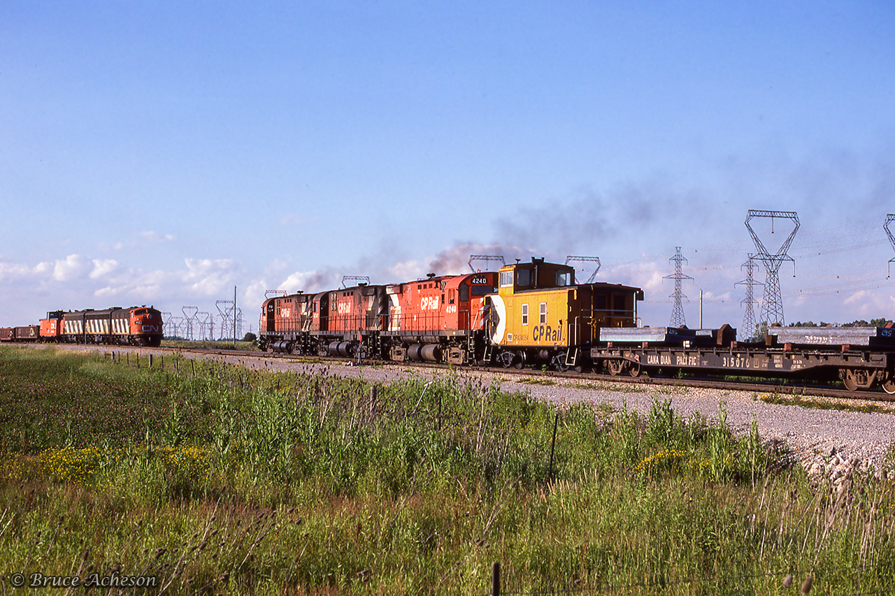 <b<A meeting of Nanticoke steel trains. Three of Canadian Pacific's MLW C424s lead the loaded train north at CN Garnet, while an A-B-A set of Canadian National GMD F7s wait in the yard to proceed south to Stelco's Lake Erie Works with empties. This scene was captured as the operation was switched between CN and CP, which occurred every so many weeks.

Per John Eull's article "The History of the Nanticoke Steel Trains - Part 2" in The Ontarian, CP's steel train was in its final year of operation before being 100% handled by CN. Prior to May 20, 1986, the train had operated Hamilton - Brantford - Waterford - Simcoe - Garnet - Nanticoke utilizing the TH&B Waterford Sub, LE&N Simcoe Sub, CN Cayuga and Hagersville Subs. A landslide at Cainsville during the evening of May 20 severed the line, which with a twelve million dollar price tag for repairs, resulted in the line being abandoned. A new route was established, operating Hamilton - Welland - Hagersville - Garnet - Nanticoke using the TH&B Welland Sub, and CN's CASO and Hagersville Subs.

The shared operation of the train between CN and CP ceased on March 22, 1987, with CN operating the train until cancellation in the fall of 1989.

More CP Steel Train:
April 1983: Meet at Waterford
November 1983: Aberdeen Departure
March 1984: Eastbound at Jarvis
April 1984: Aberdeen Yard
April 1984: Westbound at Copetown
September 1984: Over the bridge at Waterford
August 1986: Southbound at Hagersville
September 1986: Northbound at Garnet
October 1986: Departing Hamilton