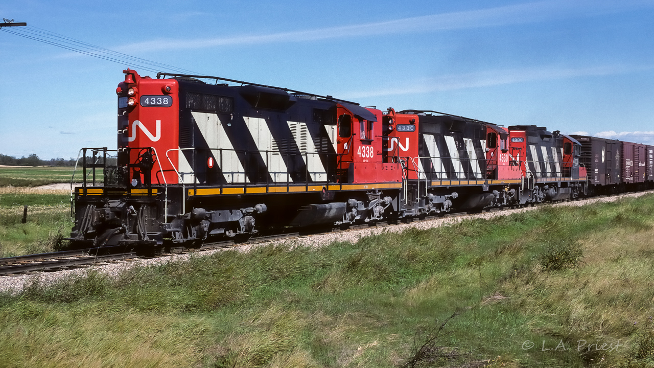The wheat symbol on the first box gives away this train. They had a quite a bunch of them too, 20 or more on the headend. Then a string of grain hoppers. That is the 4000 back there helping out. Not too uncommon, those rebuilds did turn up on occasion. Photo taken at mile 26.6, mid-afternoon.