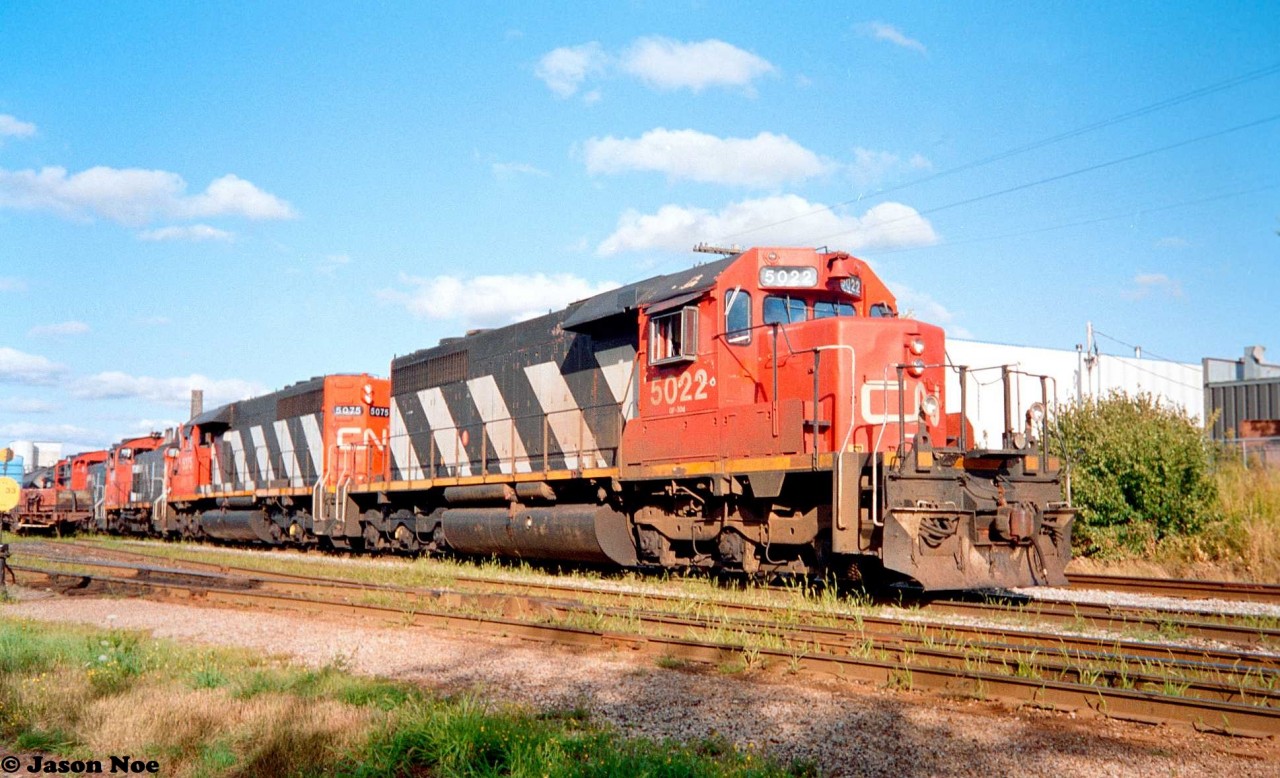 CN train 421 is viewed in the siding at the yard in Kitchener, Ontario on the Guelph Subdivision. The train was in the siding as it was meeting 88 as well as waiting for the 15:30 Kitchener Job to return from the Huron Park Spur with the loaded frame cars from the Budd Plant. That evening, 421 had quite a neat consist that included; SD40’s 5022, 5075 as well as SW1200RS/SW1200RSm’s 1386, 7307 and 7315. At the time, trains 421 and 422 often shuffled four-axle power between Toronto’s MacMillan yard and London.